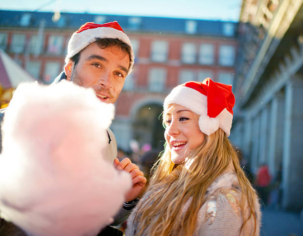 couple avec chapeau de noel qui tiennent une barbe à papa